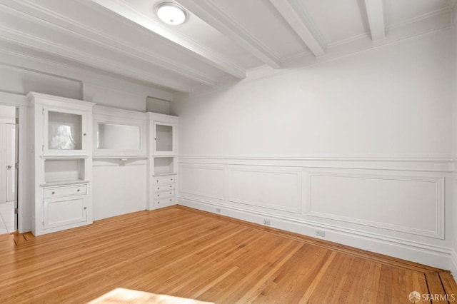 spare room featuring beamed ceiling and light wood-type flooring