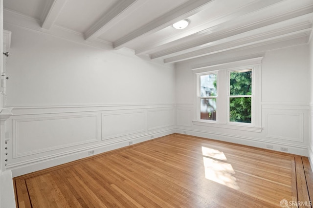 spare room featuring beamed ceiling and wood-type flooring