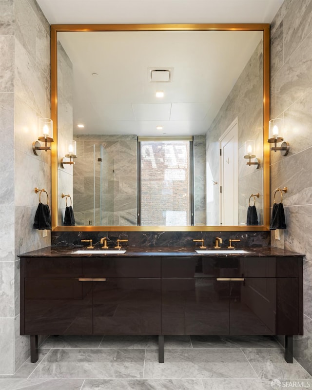 full bathroom with double vanity, tile walls, and a sink