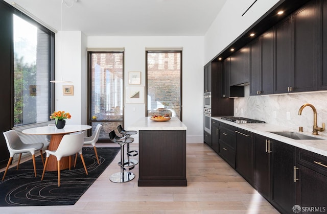 kitchen featuring a breakfast bar, a center island, stainless steel appliances, a healthy amount of sunlight, and a sink