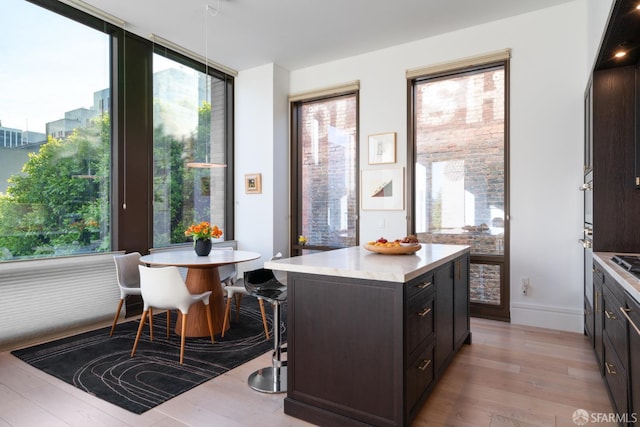 kitchen with dark brown cabinetry, baseboards, a center island, light countertops, and light wood-type flooring