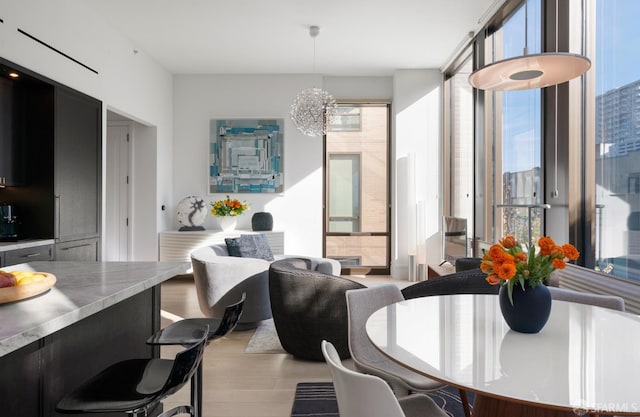 dining area with a notable chandelier, light wood finished floors, and floor to ceiling windows