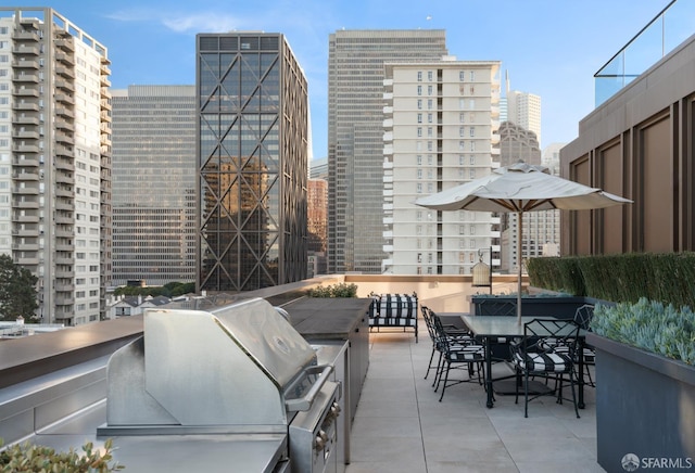 view of patio / terrace featuring a view of city, an outdoor kitchen, and a grill