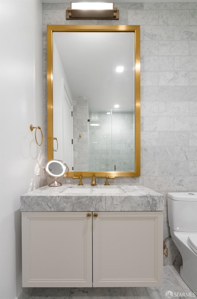 bathroom with toilet, vanity, and tile walls