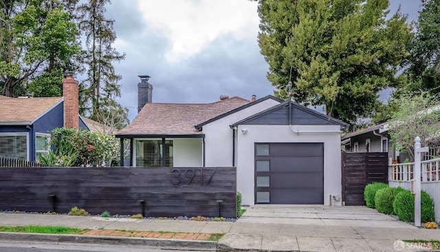 view of front of property featuring an attached garage, a fenced front yard, and stucco siding