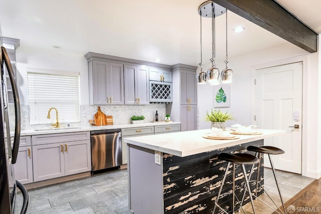 kitchen with decorative backsplash, light countertops, stainless steel appliances, gray cabinetry, and a sink