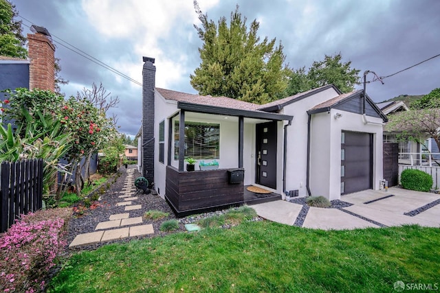 view of front of property with a chimney, stucco siding, concrete driveway, an attached garage, and fence