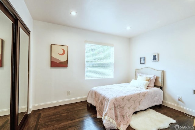 bedroom featuring dark wood-style floors, a closet, and baseboards