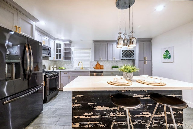 kitchen featuring decorative backsplash, gray cabinets, a sink, and black appliances