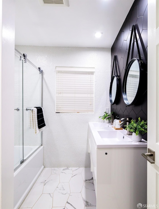 full bath with visible vents, marble finish floor, bath / shower combo with glass door, and vanity