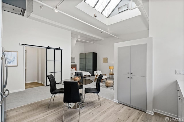 dining area with light hardwood / wood-style floors and a barn door