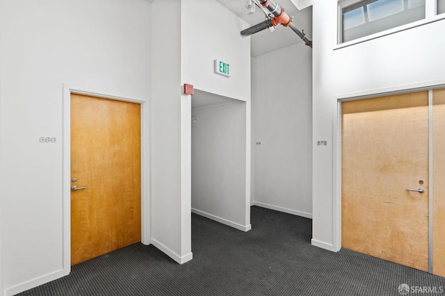 interior space featuring a barn door, dark carpet, and a high ceiling