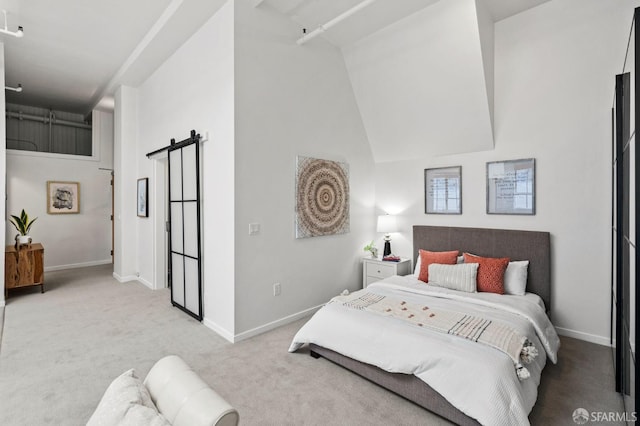 bedroom with high vaulted ceiling, light colored carpet, and a barn door