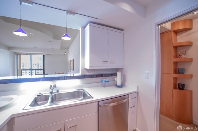 kitchen featuring pendant lighting, stainless steel dishwasher, white cabinetry, and sink