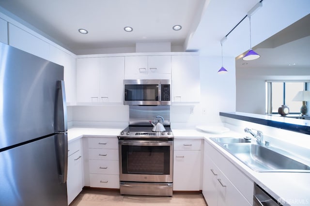 kitchen featuring sink, white cabinets, hanging light fixtures, and appliances with stainless steel finishes