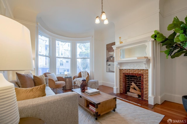 living room with a brick fireplace, light hardwood / wood-style floors, and a notable chandelier