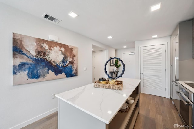 1605 Riviera Ave Unit 608, Walnut Creek, CA 94596 - kitchen featuring oven, wood finished floors, light stone counters, a kitchen island, and recessed lighting