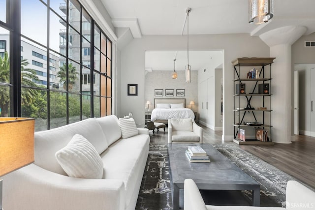 living room with a healthy amount of sunlight, visible vents, baseboards, and wood finished floors