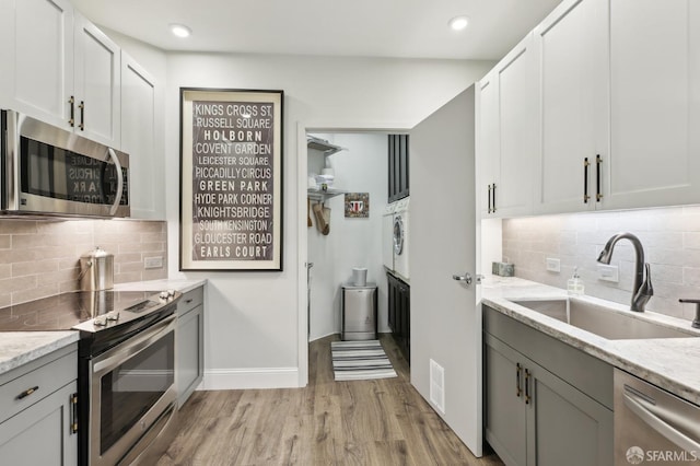 kitchen with light wood-style flooring, a sink, visible vents, appliances with stainless steel finishes, and light stone countertops