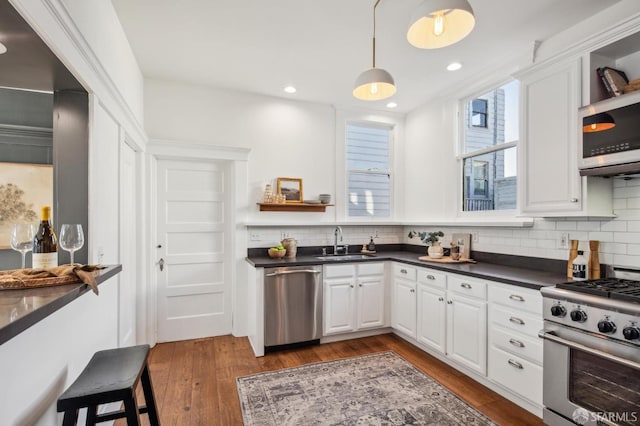 kitchen featuring backsplash, sink, dark wood-type flooring, stainless steel appliances, and white cabinets