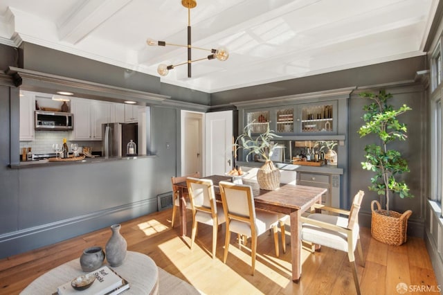 dining room with beam ceiling, a notable chandelier, crown molding, and light hardwood / wood-style flooring