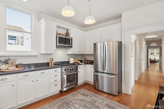 kitchen with appliances with stainless steel finishes, pendant lighting, decorative backsplash, and white cabinetry