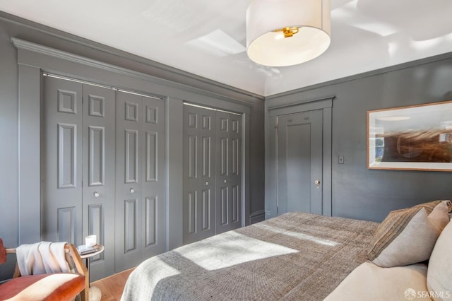 bedroom featuring ornamental molding and multiple closets