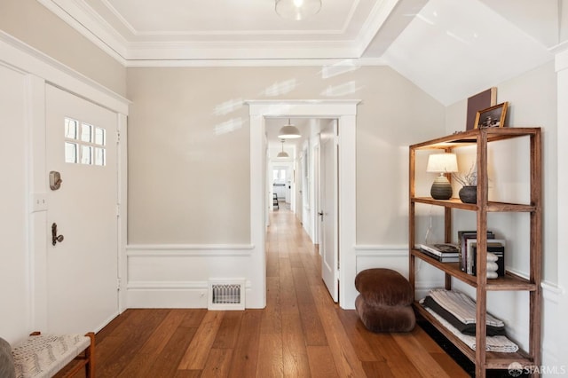 entryway with wood-type flooring, ornamental molding, and lofted ceiling