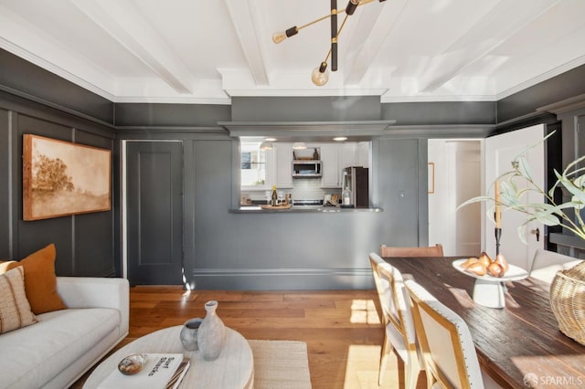 living room featuring ornamental molding, beam ceiling, hardwood / wood-style floors, and a chandelier