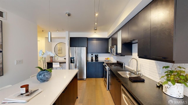 kitchen with pendant lighting, light wood-type flooring, stainless steel appliances, and sink