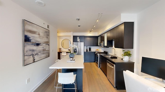 kitchen with a kitchen breakfast bar, light wood-type flooring, sink, and appliances with stainless steel finishes