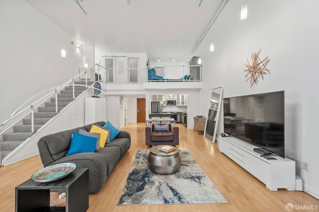 living room with stairway, wood finished floors, and a towering ceiling