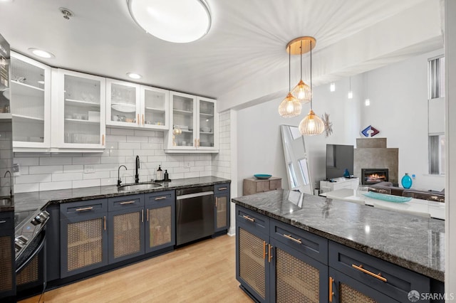 kitchen featuring backsplash, blue cabinetry, stainless steel dishwasher, a sink, and white cabinets