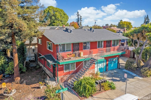5020 Clarke St, Oakland, CA 94609 - view of front of house featuring an attached garage, roof with shingles, driveway, and stairway