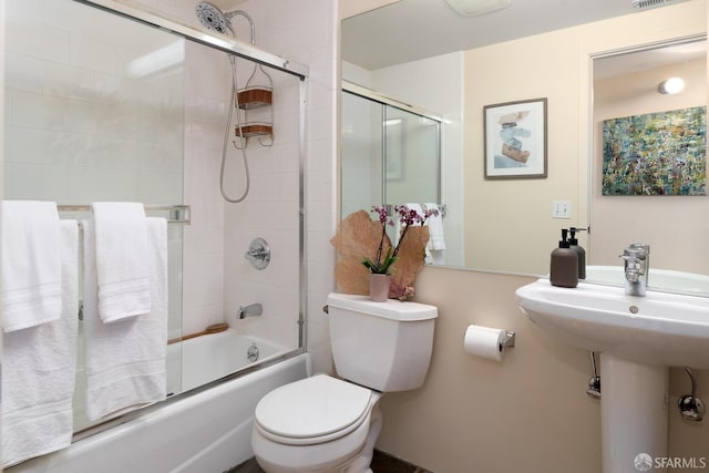 bathroom featuring toilet and combined bath / shower with glass door