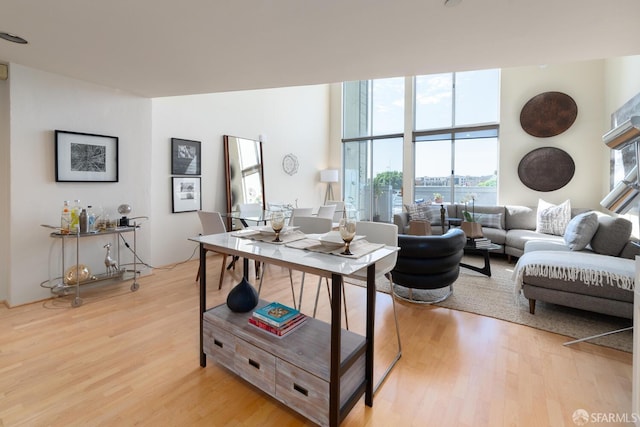 living room with floor to ceiling windows, a water view, and light wood-type flooring