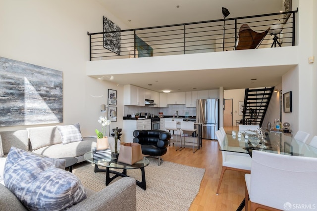 living room featuring a towering ceiling and light wood-type flooring