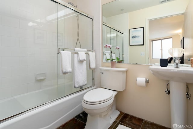 bathroom with toilet and combined bath / shower with glass door