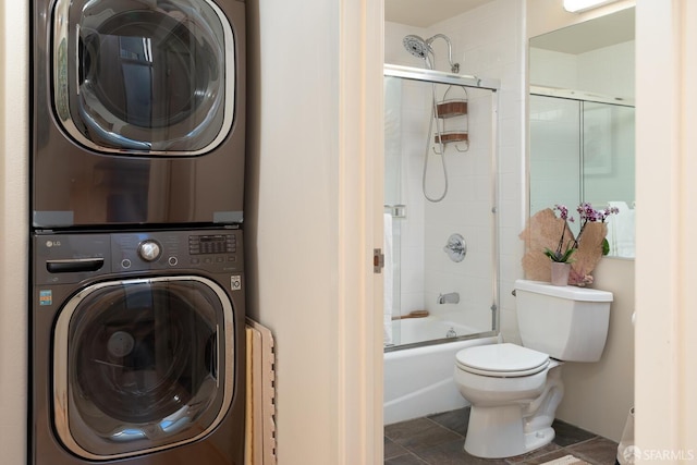 laundry area featuring dark tile patterned floors and stacked washer and clothes dryer