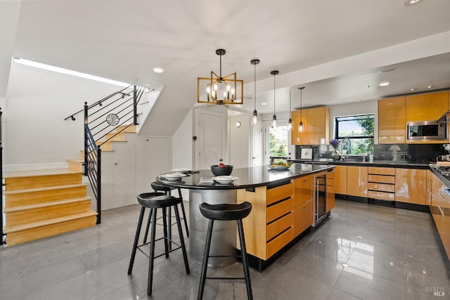 kitchen with dark countertops, a breakfast bar, stainless steel microwave, decorative backsplash, and modern cabinets