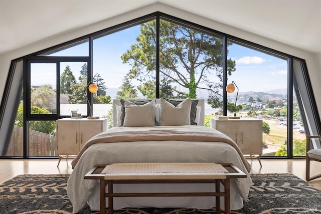 bedroom with multiple windows, wood finished floors, and lofted ceiling