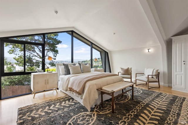 bedroom with light wood-style floors, baseboards, and lofted ceiling