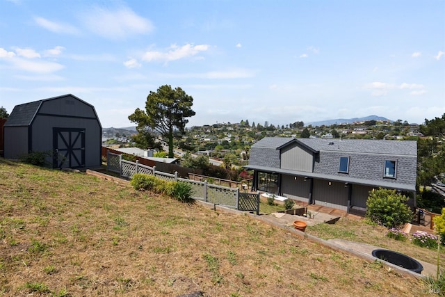 view of yard with fence, a storage unit, an outdoor structure, and a mountain view