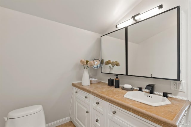 bathroom with vanity, lofted ceiling, and toilet