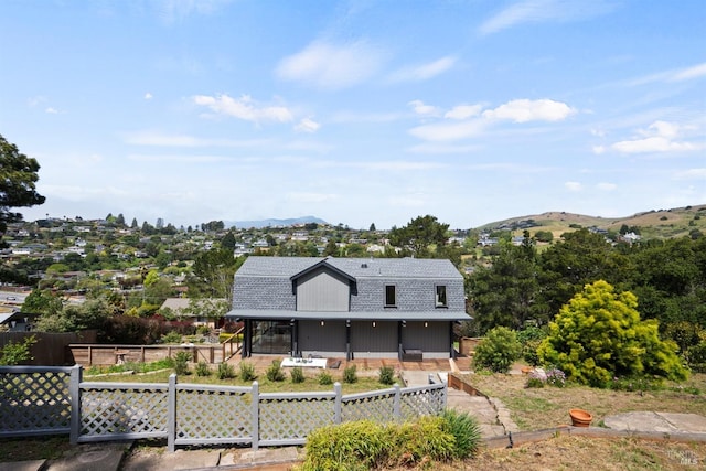 back of property with a mountain view, fence private yard, and roof with shingles