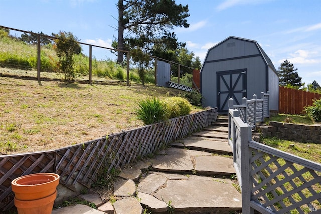 view of yard featuring fence, a storage unit, and an outdoor structure