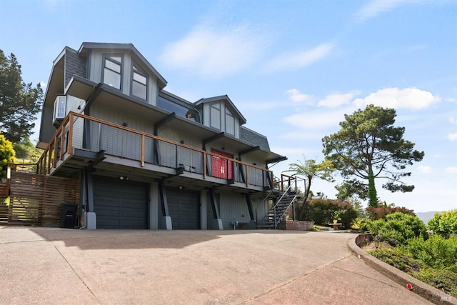 exterior space with concrete driveway, an attached garage, stairs, and a balcony