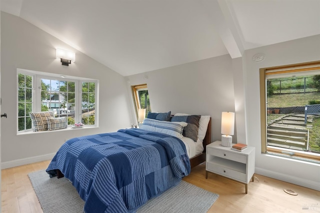 bedroom with baseboards, multiple windows, vaulted ceiling, and light wood-style flooring