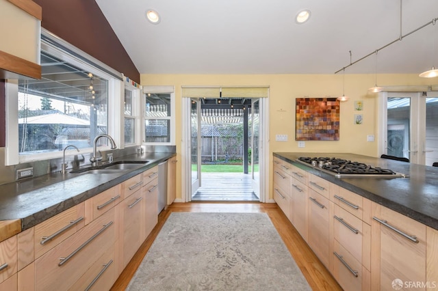 kitchen featuring hanging light fixtures, stainless steel gas stovetop, light brown cabinetry, light wood-type flooring, and sink