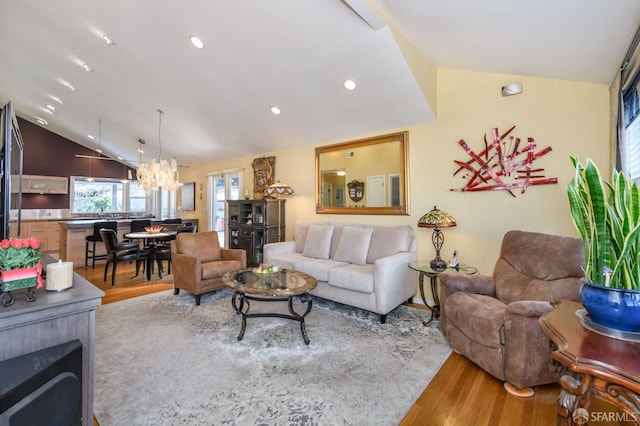 living room with a chandelier, vaulted ceiling, and light wood-type flooring